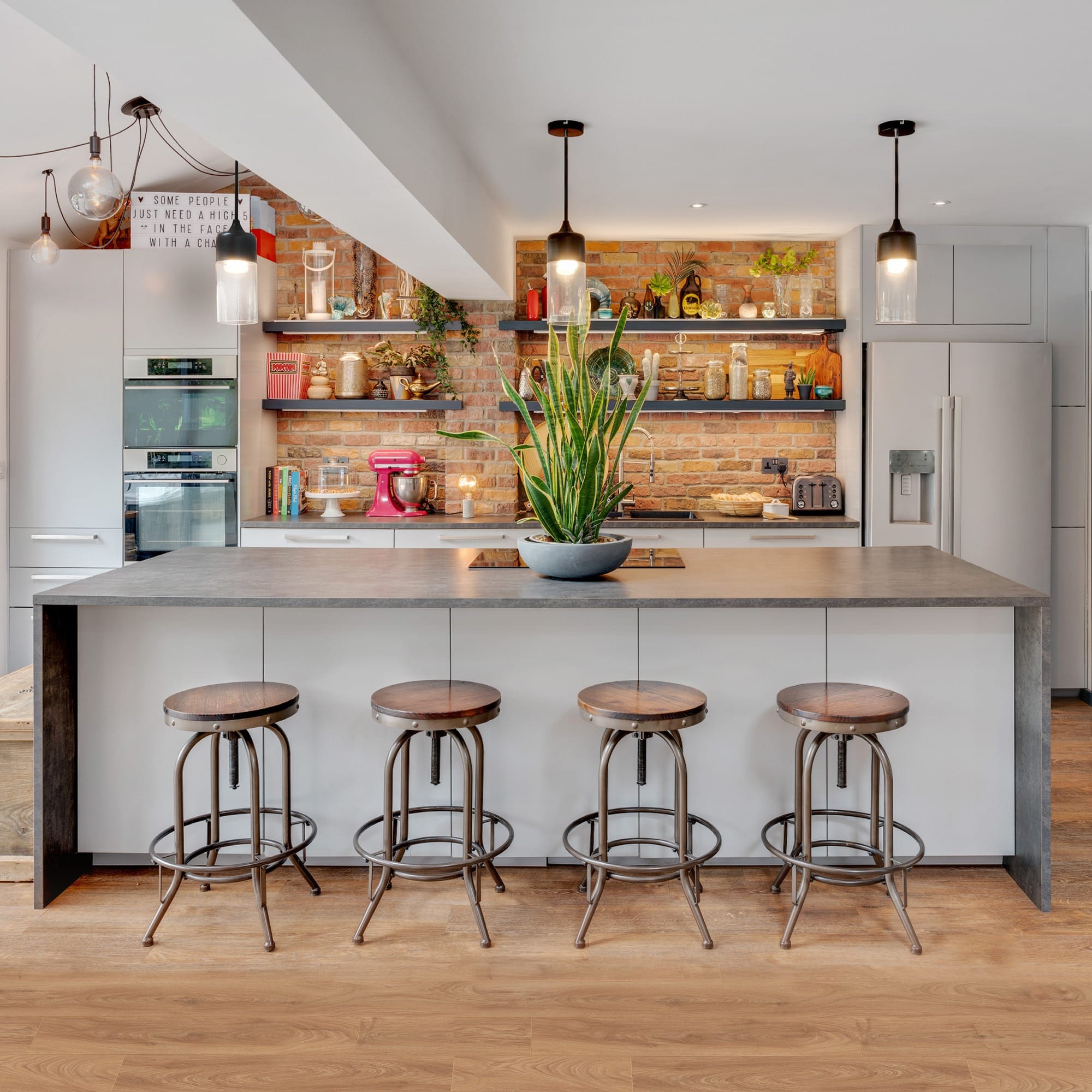 Open-plan kitchen extension designed by Inner Create in Milton Keynes, featuring industrial bar stools, exposed brick walls, and energy-efficient design elements